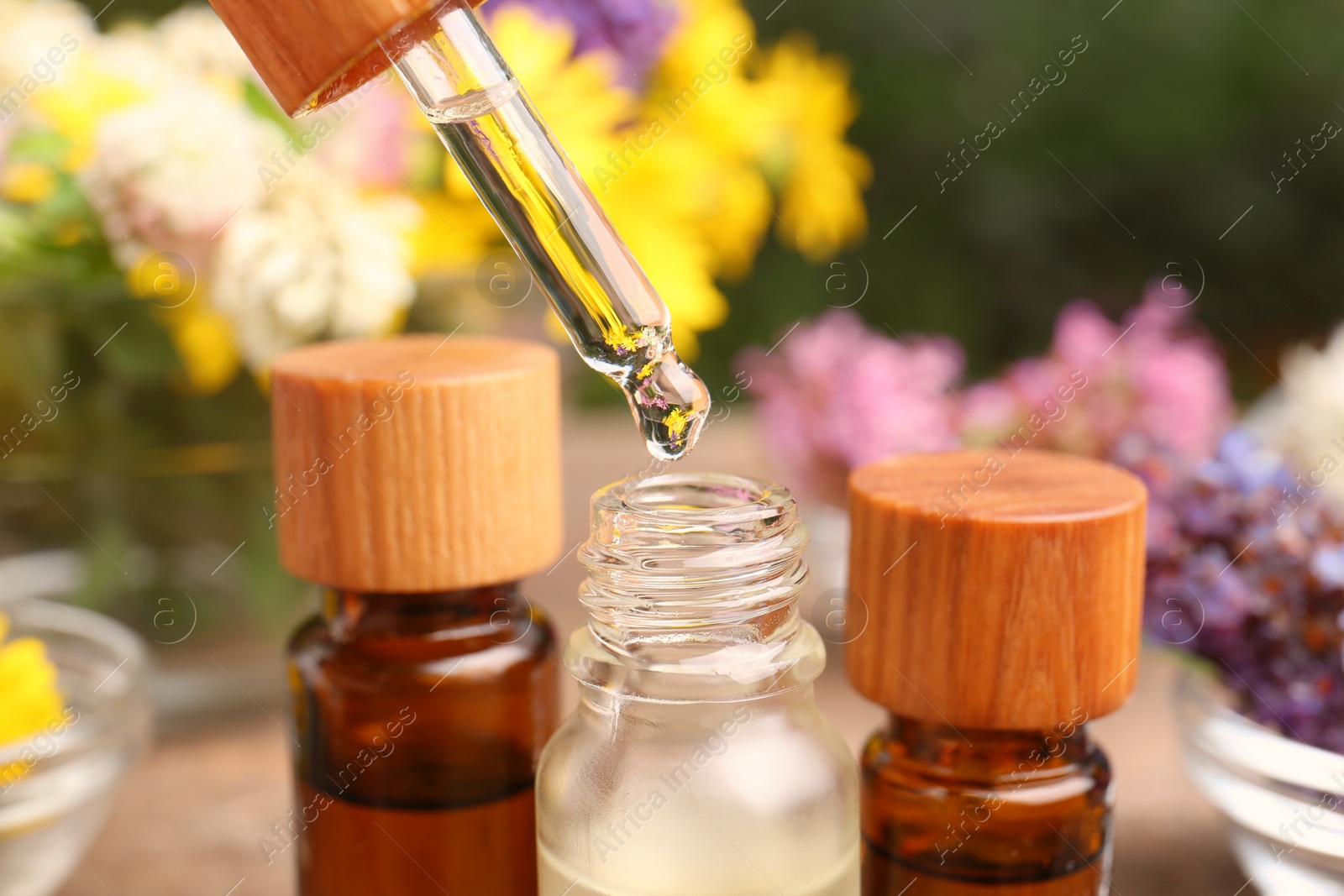 Photo of Dripping essential oil from pipette into bottle, closeup