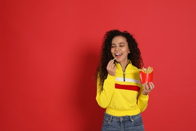 Photo of African American woman eating French fries on red background, space for text
