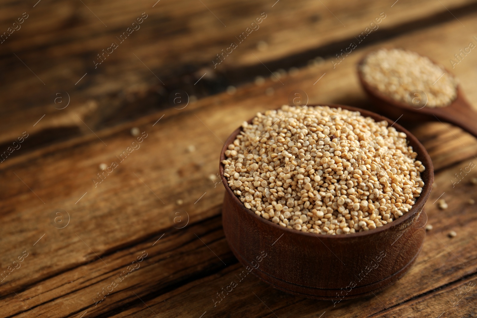 Photo of Bowl with white quinoa on wooden table. Space for text