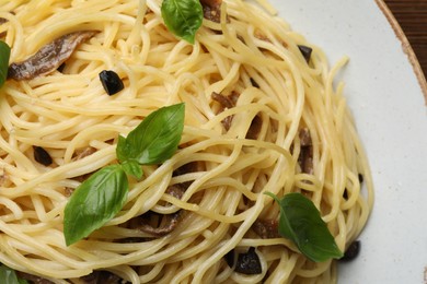 Delicious pasta with anchovies, olives and basil on plate, closeup