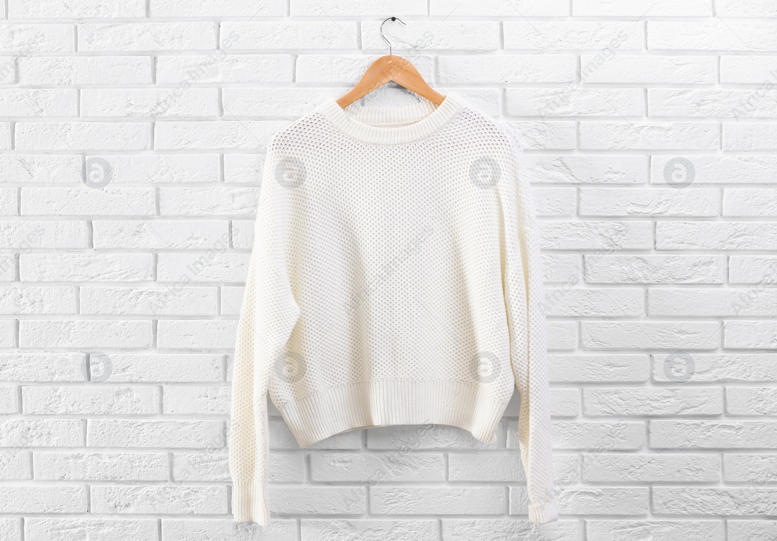 Photo of Hanger with stylish sweater on brick wall