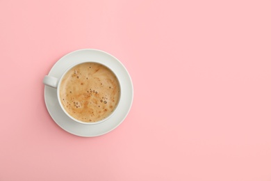 Cup of coffee on pink background, top view. Space for text