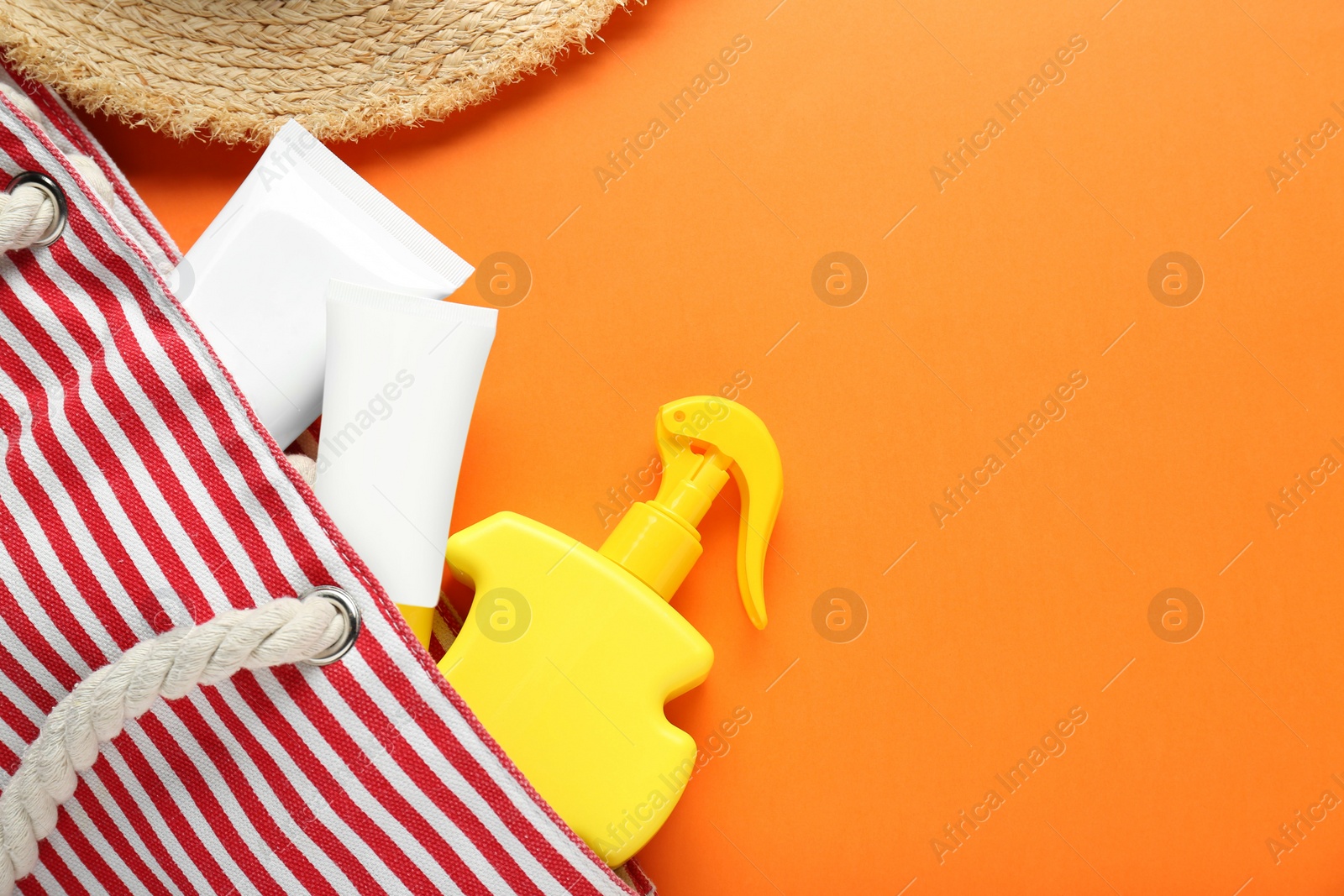 Photo of Suntan products in bag on orange background, flat lay. Space for text