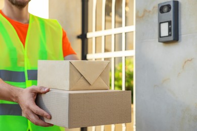 Photo of Courier in uniform with two parcels outdoors, closeup