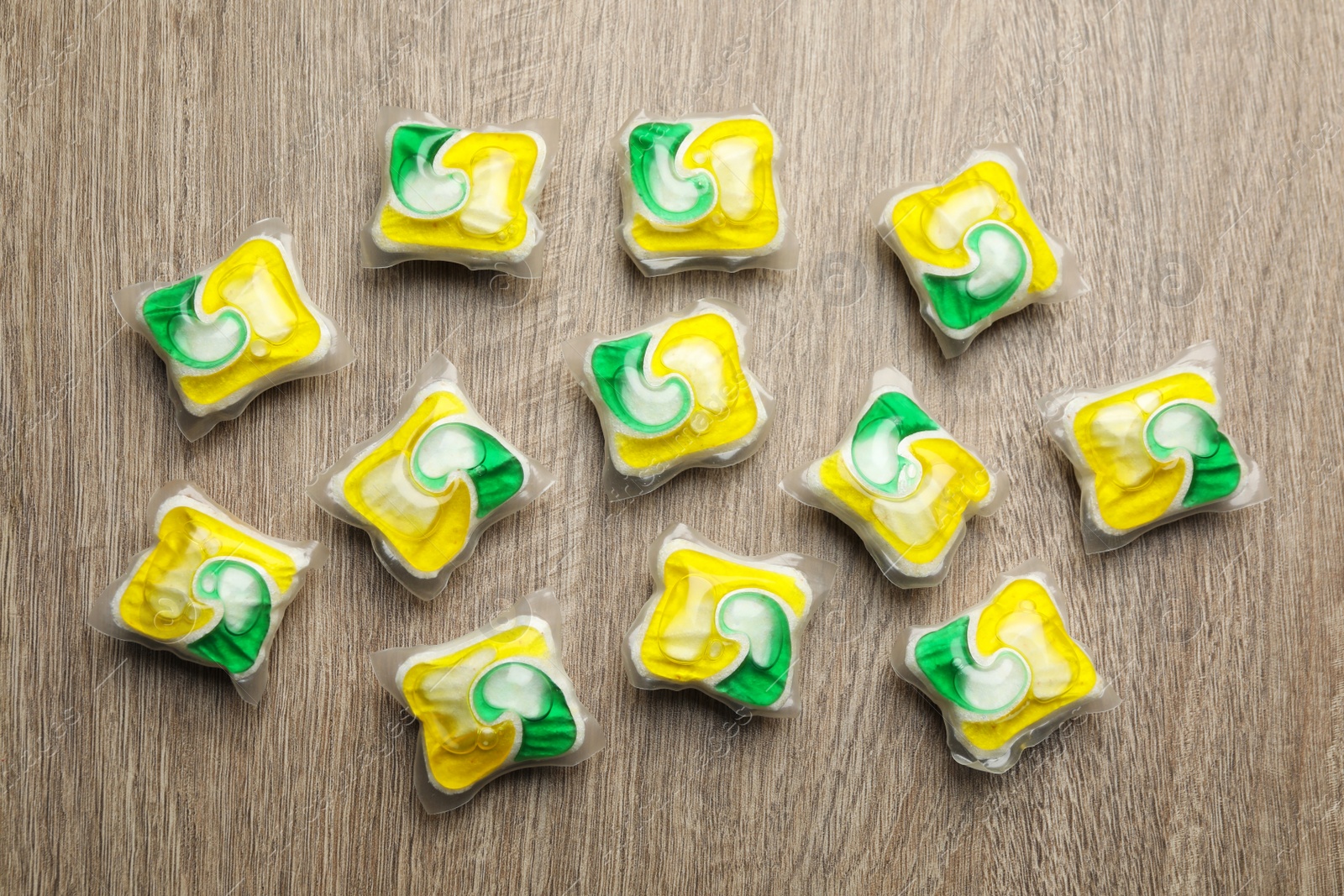 Photo of Many dishwasher detergent pods on wooden table, flat lay