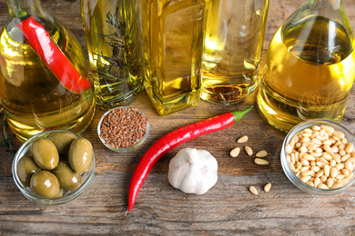 Photo of Different cooking oils in bottles on wooden table