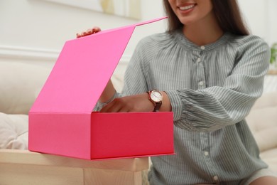 Photo of Happy young woman opening parcel at home, closeup. Internet shopping