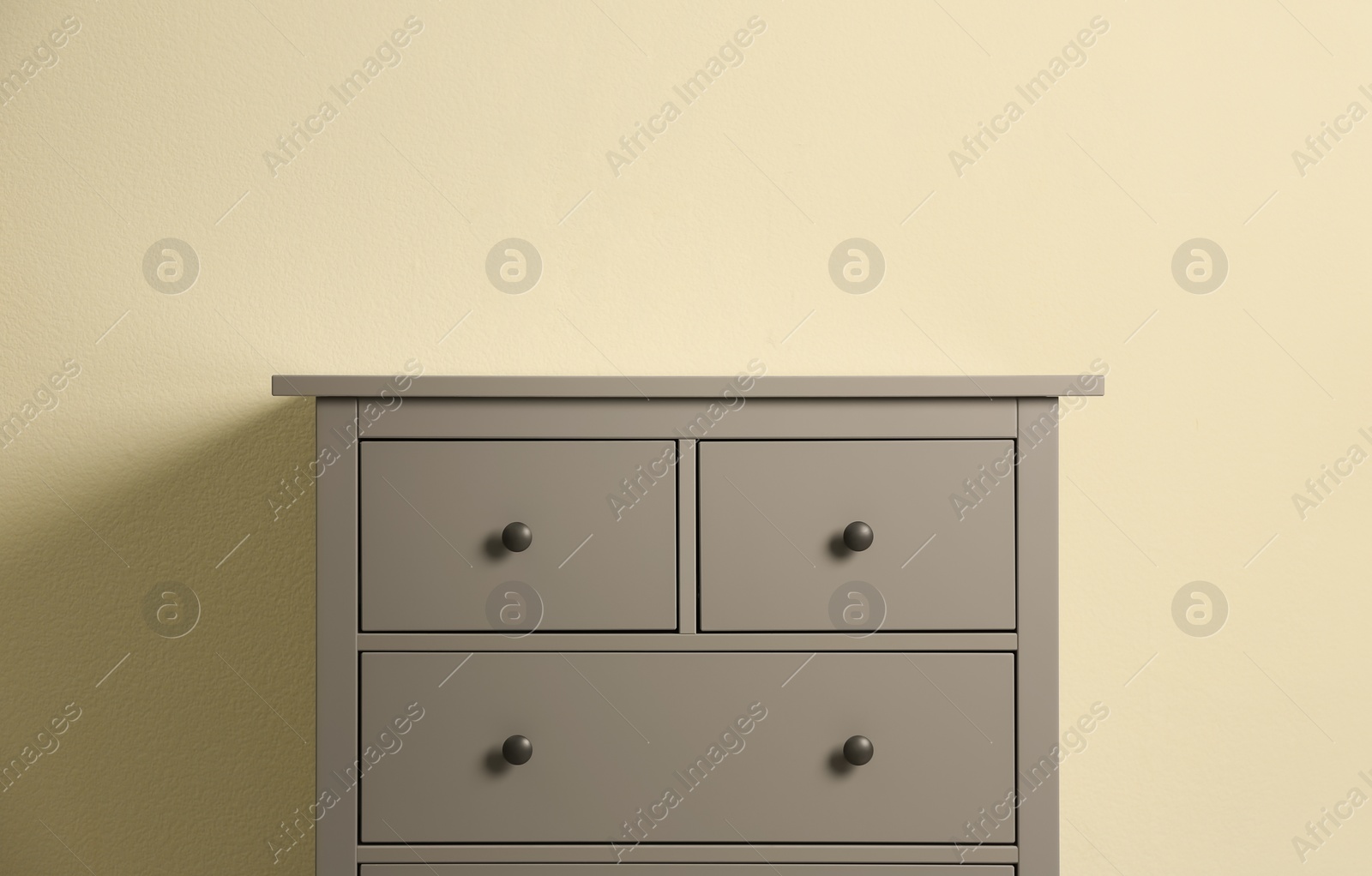 Photo of Grey chest of drawers on beige background