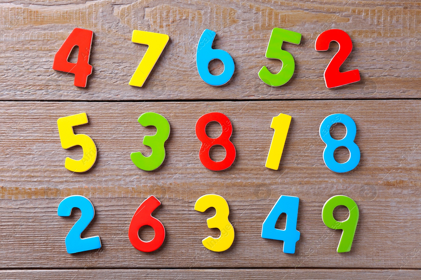 Photo of Colorful numbers on wooden table, flat lay