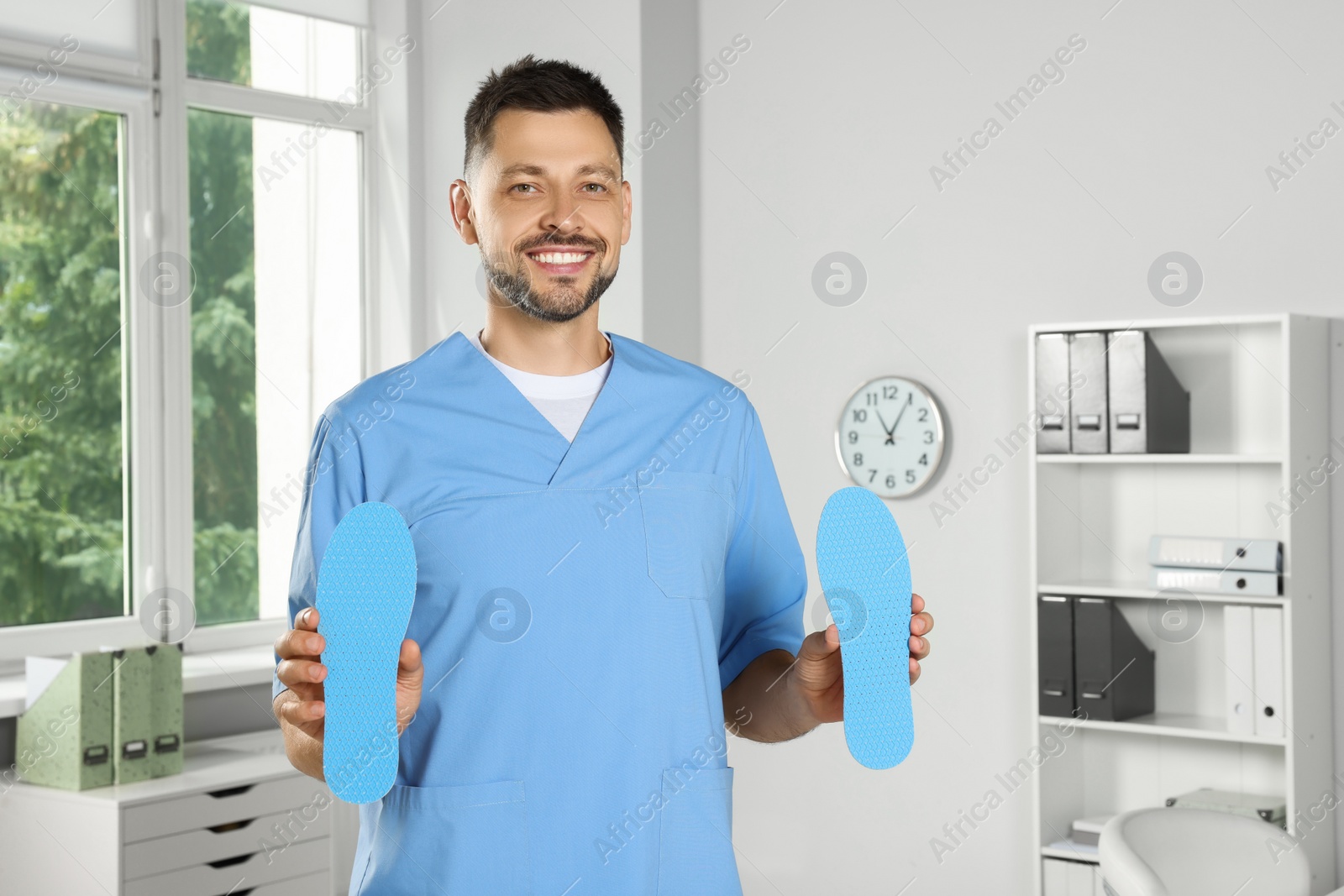 Photo of Handsome male orthopedist showing insoles in hospital