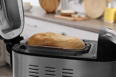 Photo of Fresh homemade bread in open breadmaker machine, closeup