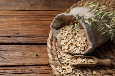 Photo of Scoop, bag with oatmeal and florets on wooden table, space for text