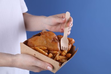 Photo of Woman eating fish and chips on blue background, closeup. Space for text