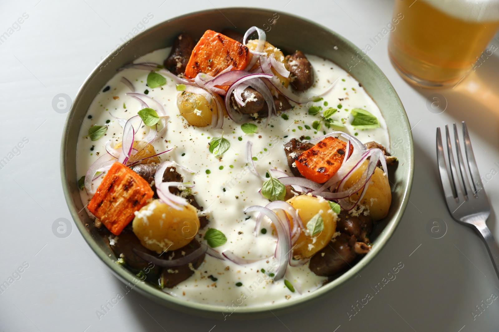 Photo of Beer and tasty dish served on light table, above view