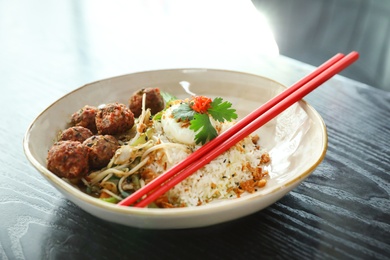 Photo of Plate with rice, meat balls and chopsticks served on table