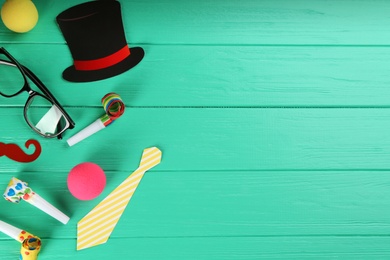 Flat lay composition with clown's items on turquoise wooden table, space for text
