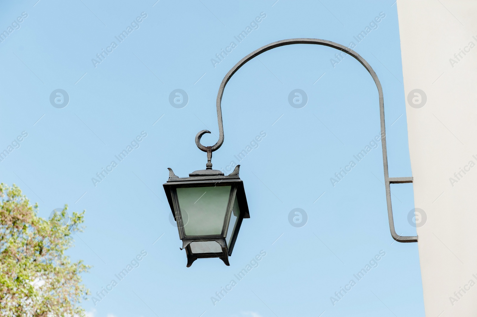 Photo of Vintage street lamp on wall of building against blue sky, low angle view