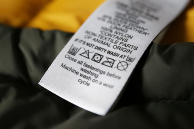 Photo of Clothing label with care symbols on color jacket, closeup view