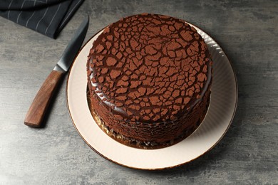 Photo of Delicious chocolate truffle cake and knife on grey textured table