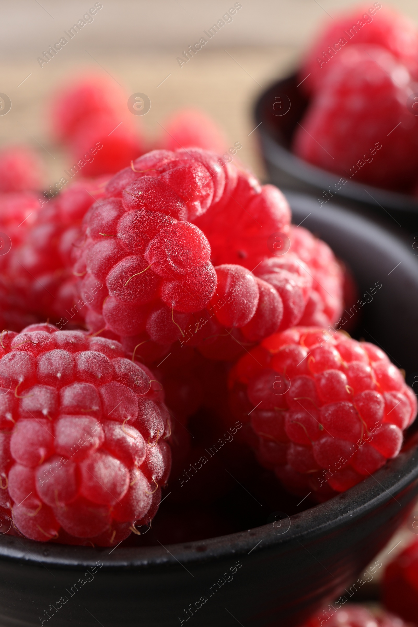 Photo of Tasty ripe raspberries in black bowl, closeup