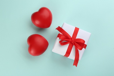 Photo of Beautiful gift box and red hearts on turquoise background, flat lay. Valentine's day celebration