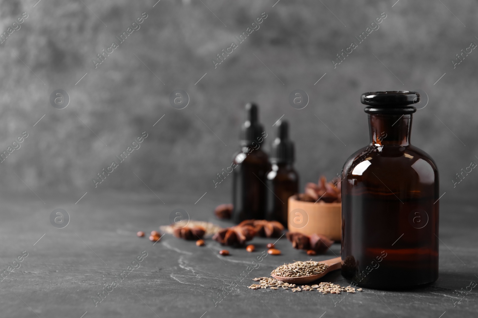 Photo of Bottles of anise essential oil and seeds on black table. Space for text