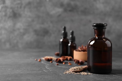 Bottles of anise essential oil and seeds on black table. Space for text