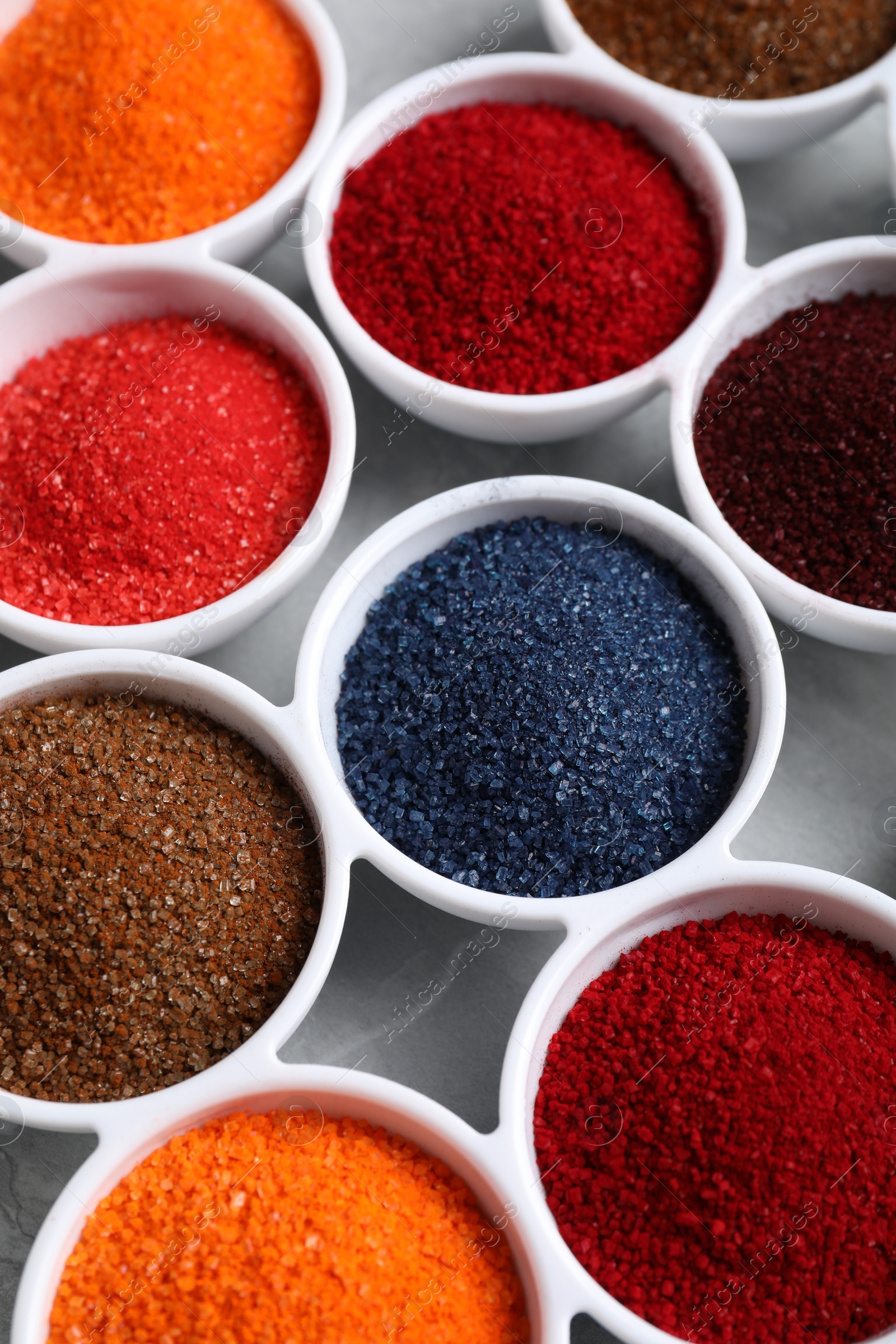 Photo of Bowls of different food coloring on light grey table, closeup