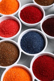 Photo of Bowls of different food coloring on light grey table, closeup