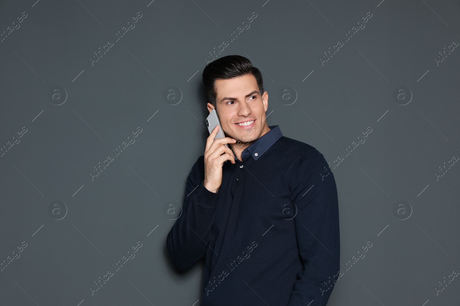 Photo of Portrait of handsome man talking on phone against grey background