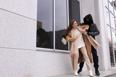Photo of Woman fighting with thief while he trying to steal her bag near building, space for text. Self defense concept