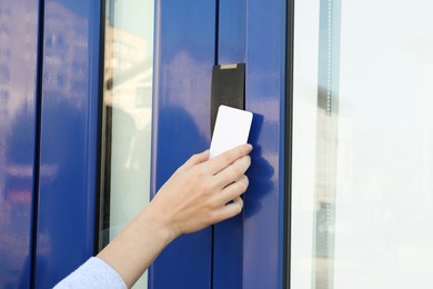 Photo of Woman opening magnetic door lock with key card outdoors, closeup