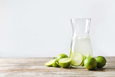 Photo of Natural lemonade with lime in bottle on wooden table