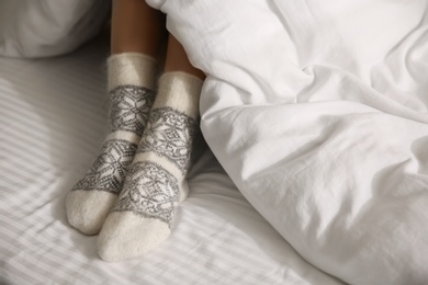 Woman wearing knitted socks under blanket in bed, closeup