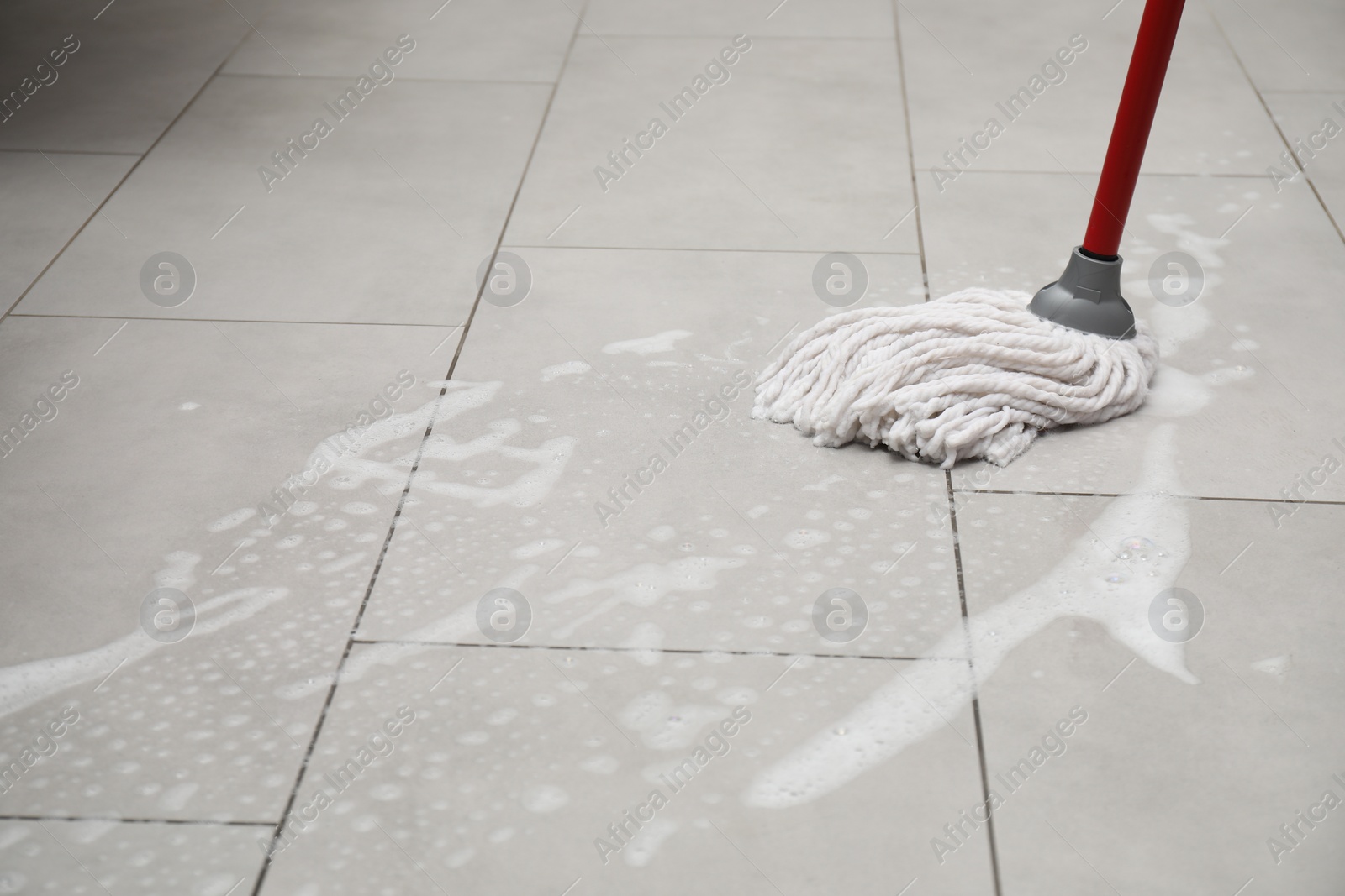 Photo of Cleaning grey tiled floor with string mop, space for text