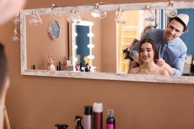 Photo of Reflection of professional hairdresser working with client in beauty salon