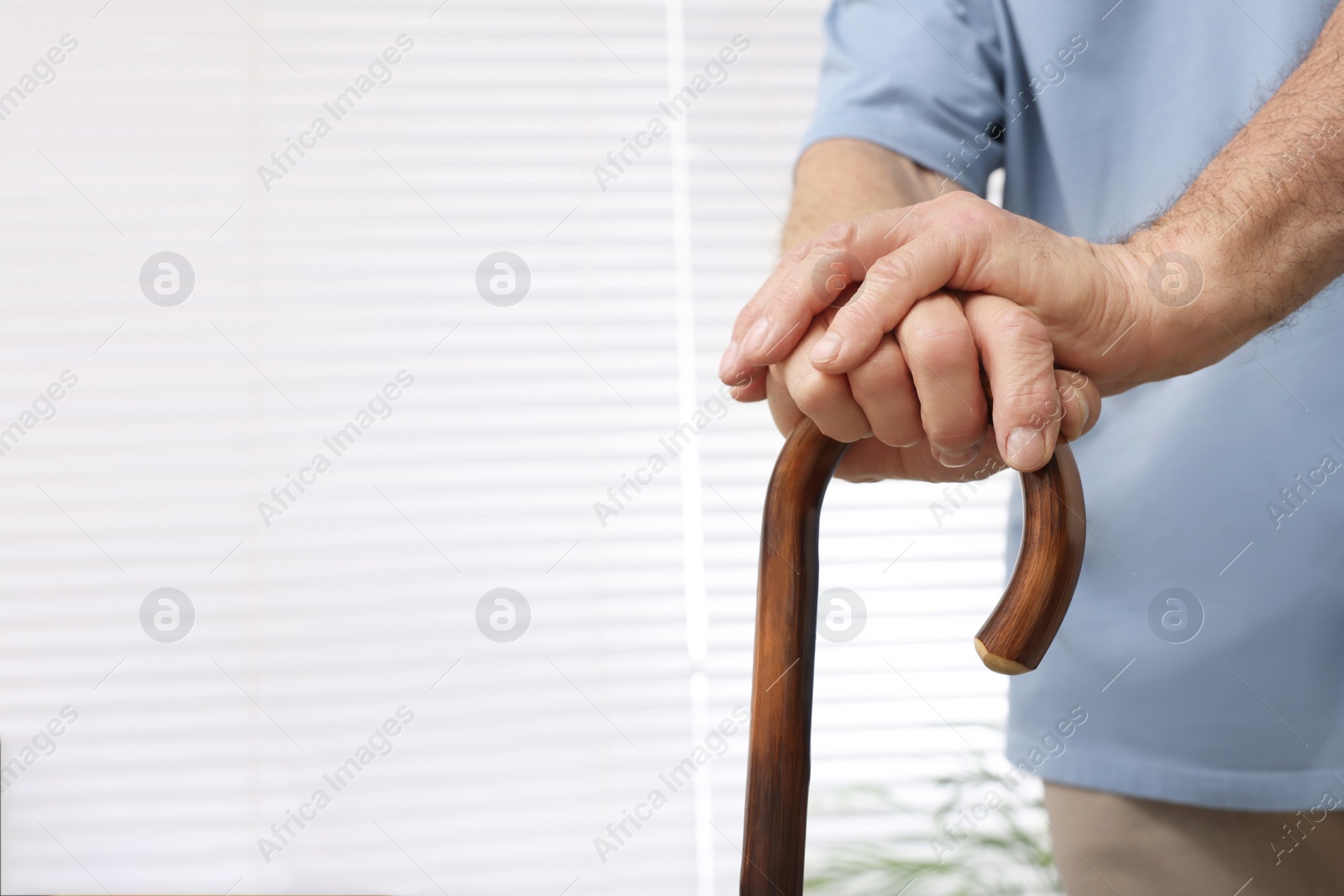 Photo of Senior man with walking cane at home, closeup. Space for text