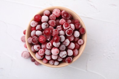 Frozen red cranberries in bowl on white table, top view