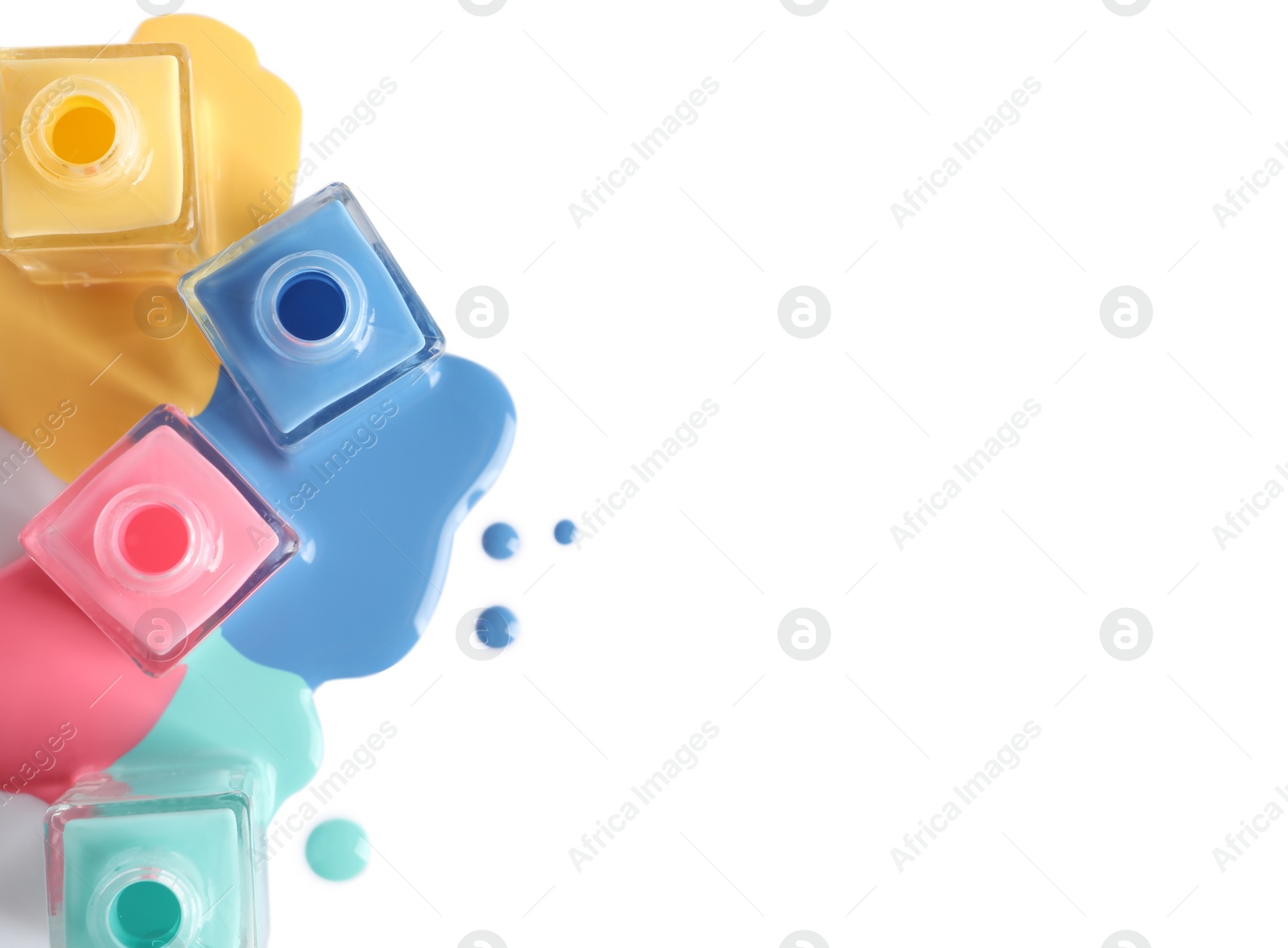 Photo of Spilled different nail polishes with bottles on white background, top view