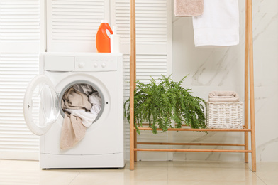 Modern washing machine with towels in bathroom