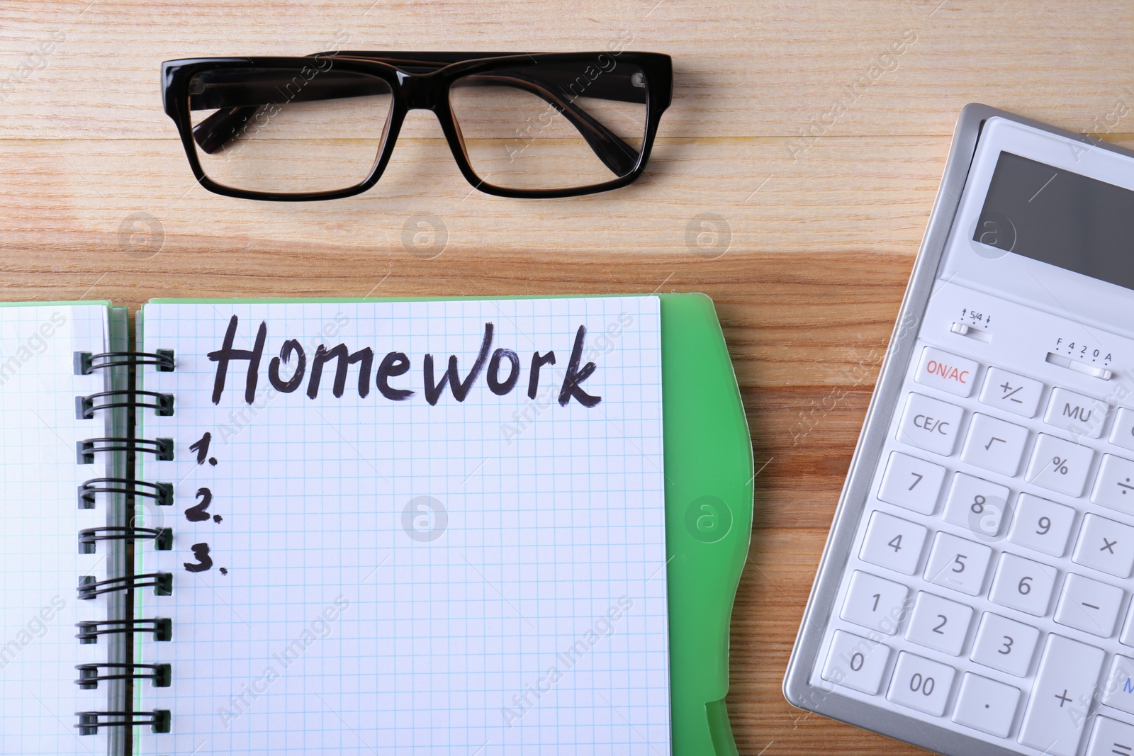 Photo of Word HOMEWORK in notebook, glasses and calculator on wooden table, flat lay