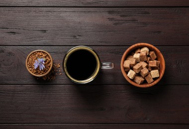Photo of Glass cup of delicious chicory drink, granules, brown sugar and flower on wooden table, flat lay