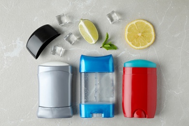 Flat lay composition with different male deodorants on light grey marble table