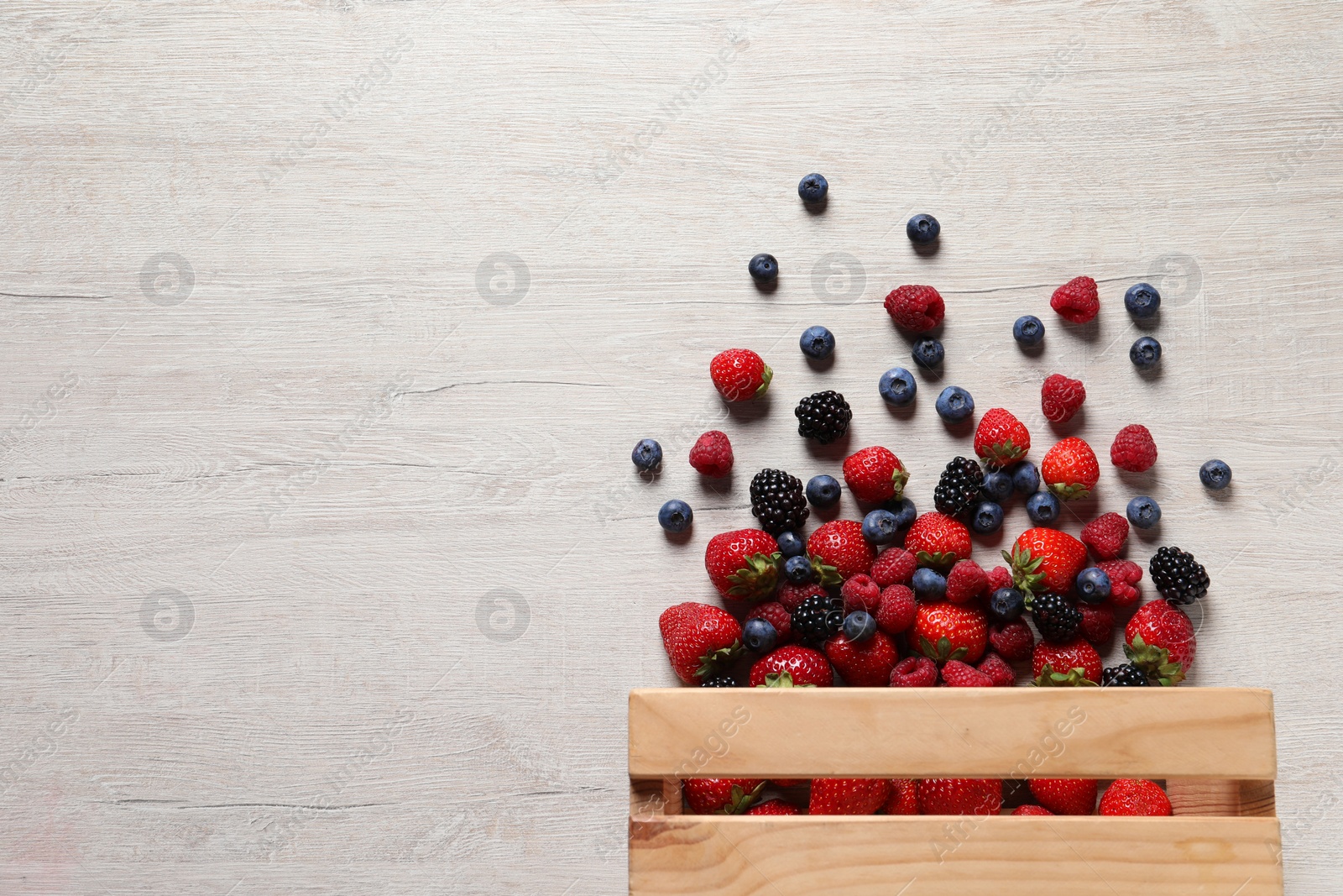 Photo of Different fresh ripe berries on light wooden table, flat lay. Space for text