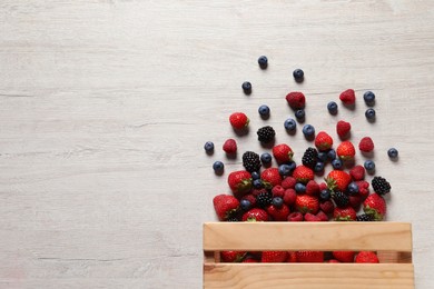 Photo of Different fresh ripe berries on light wooden table, flat lay. Space for text