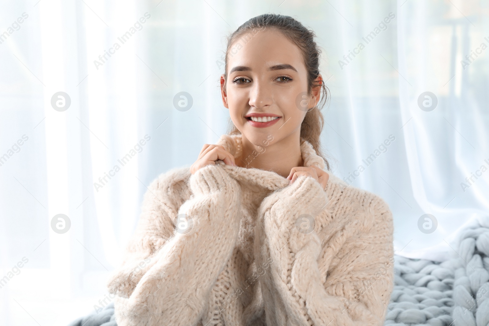 Photo of Portrait of beautiful teenage girl in warm cozy sweater on light background