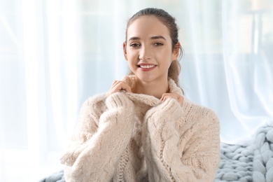 Photo of Portrait of beautiful teenage girl in warm cozy sweater on light background