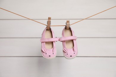 Photo of Pink baby shoes drying on washing line against white wall