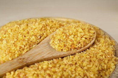 Photo of Bowl and spoon of uncooked bulgur, closeup view