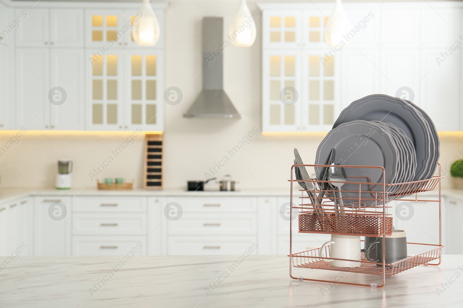 Photo of Drying rack with clean dishes on table in kitchen. Space for text